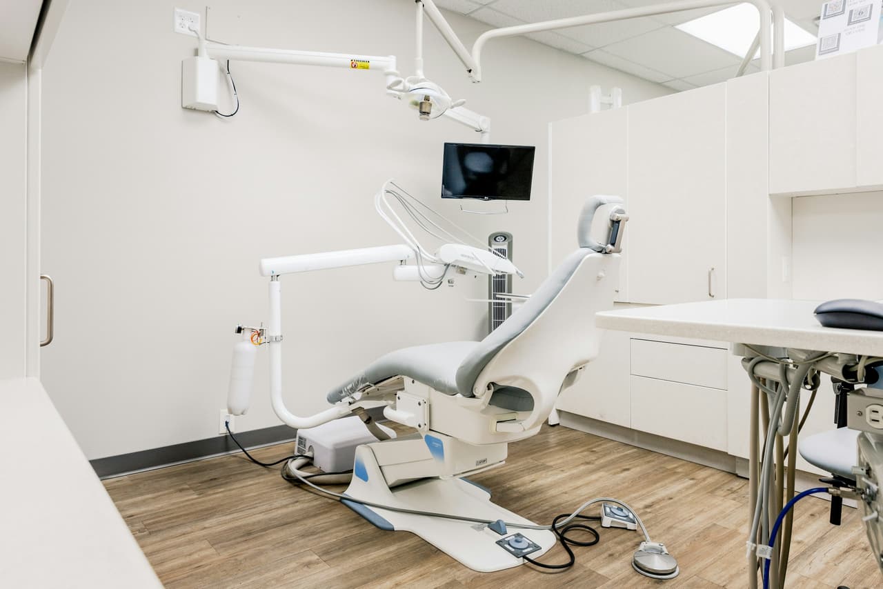 Sala de atendimento clara com mesa e cadeiras ao lado do consultório