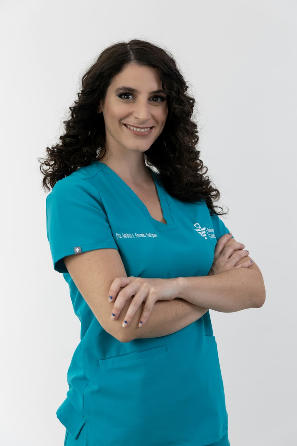 Dentista de cabelos cacheados com uniforme verde-água, de braços cruzados