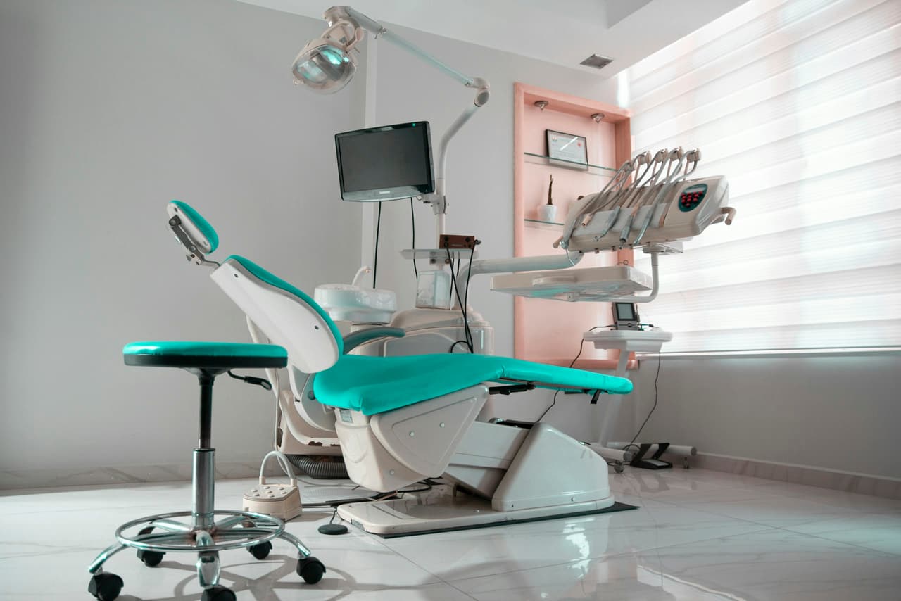 Consultório com cadeira odontológica, monitor e iluminação clara