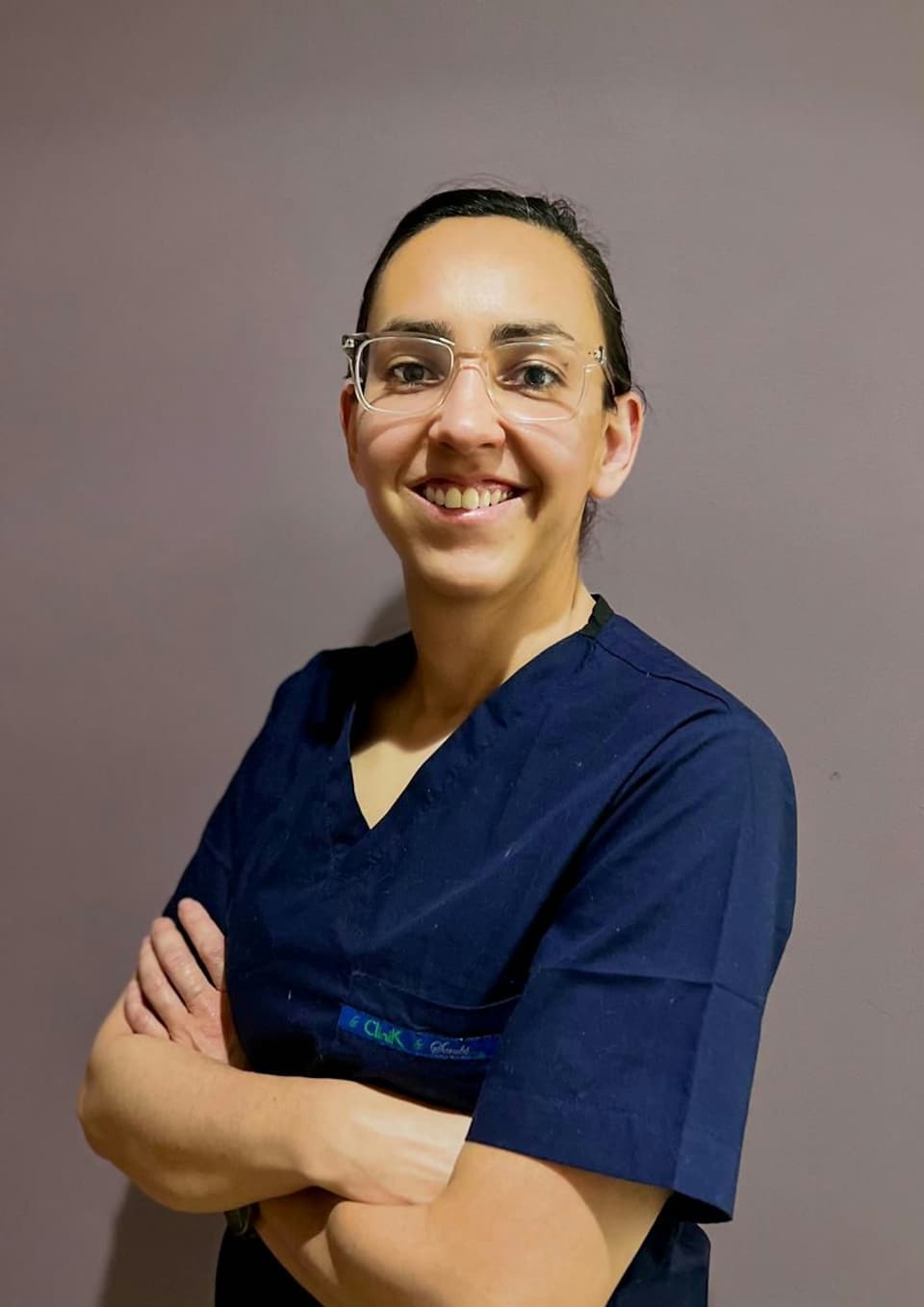 Dentista de óculos e uniforme azul sorrindo